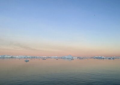 View of sun setting behind icebergs